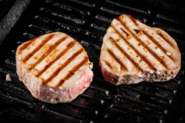 Tuna steak in a grill pan. On a black background. High quality photo
