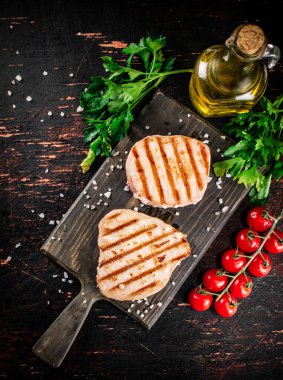 Grilled tuna on a cutting board with parsley and tomatoes. Against a dark background. High quality photo