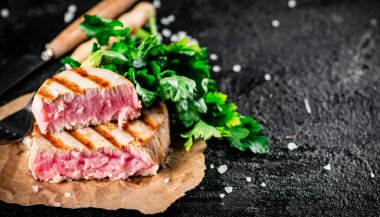 Grilled tuna with parsley on the table. On a black background. High quality photo