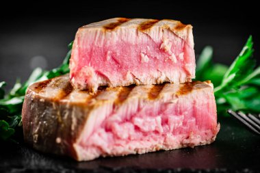 Grilled tuna with parsley on the table. On a black background. High quality photo