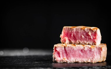 Grilled tuna steak on the table. On a black background. High quality photo