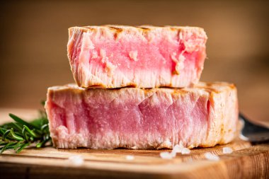 A piece of grilled tuna on a cutting board. On a wooden background. High quality photo