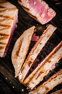 Grilled tuna on a cutting board. Against a dark background. High quality photo