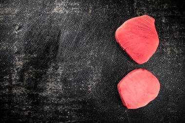 Raw tuna steak on the table. On a black background. High quality photo