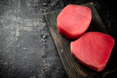 A fresh piece of raw tuna on a cutting board. On a black background. High quality photo