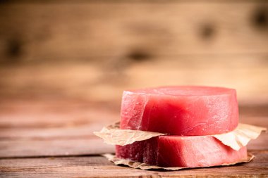 Raw tuna steak with paper on the table. On a wooden background. High quality photo