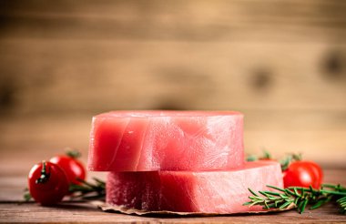 Raw tuna with cherry tomatoes and rosemary. On a wooden background. High quality photo
