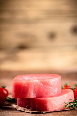 Raw tuna with cherry tomatoes and rosemary. On a wooden background. High quality photo