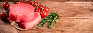 Raw tuna with cherry tomatoes and rosemary. On a wooden background. High quality photo