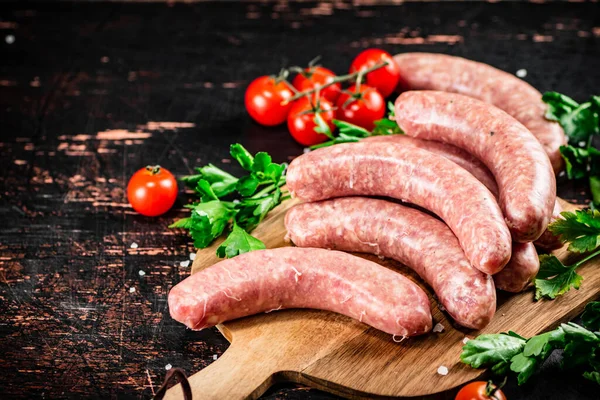 Raw Sausages Wooden Cutting Board Tomatoes Herbs Dark Background High — Stok fotoğraf