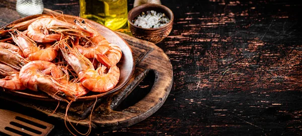 Boiled shrimp in a plate on a cutting board with spices. On a rustic dark background. High quality photo