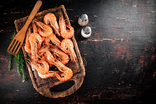 stock image Cooked shrimp on a cutting board with spices and rosemary. Against a dark background. High quality photo