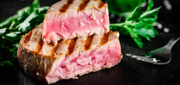 stock image Grilled tuna with parsley on the table. On a black background. High quality photo