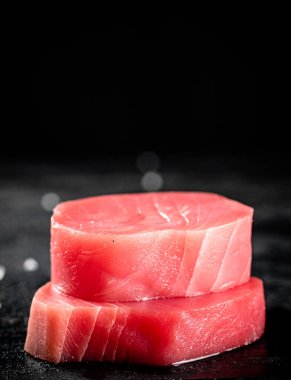 Raw tuna steaks on the table. On a black background. High quality photo