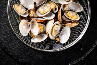 Vongole in a colander on a stone board. On a black background. High quality photo