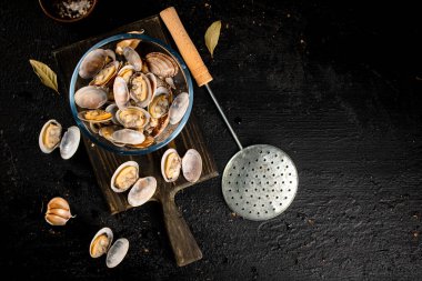 Vongole in a glass bowl on a cutting board. On a black background. High quality photo