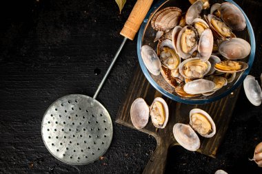 Vongole in a glass bowl on a cutting board. On a black background. High quality photo