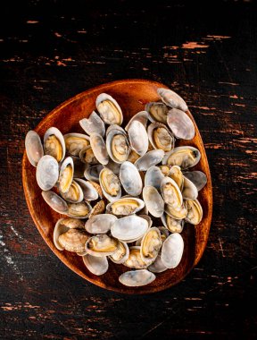 A wooden plate full of fresh vongole. Against a dark background. High quality photo