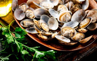 Vongole on a wooden plate with parsley. On a rustic dark background. High quality photo