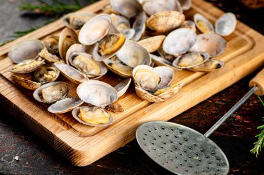 Vongole on a wooden cutting board. Against a dark background. High quality photo