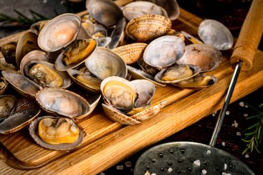 Vongole on a wooden cutting board. Against a dark background. High quality photo