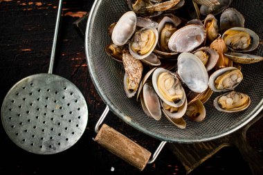 Vongole in a colander on a cutting board. On a rustic dark background. High quality photo