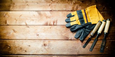 Chisel with construction gloves on the table. On a wooden background. High quality photo