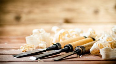 Chisel with a bunch of wood sawdust. On a wooden background. High quality photo
