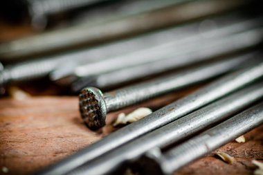 A bunch of nails on the table. On a wooden background. High quality photo