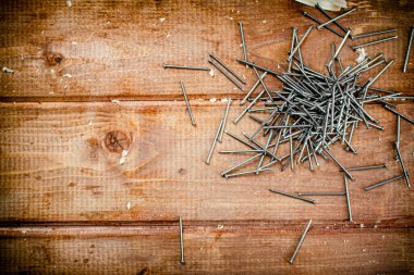 A pile of nails on the table. On a wooden background. High quality photo