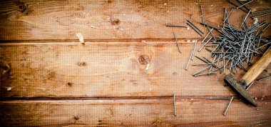 Hammer with a bunch of nails on the table. On a wooden background. High quality photo