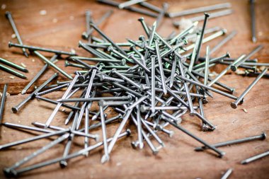 A pile of nails on the table. On a wooden background. High quality photo