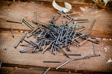 A pile of nails on the table. On a wooden background. High quality photo