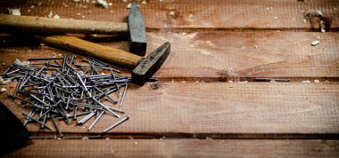 Hammer with a bunch of nails on the table. On a wooden background. High quality photo