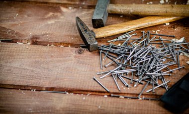 Hammer with a bunch of nails on the table. On a wooden background. High quality photo
