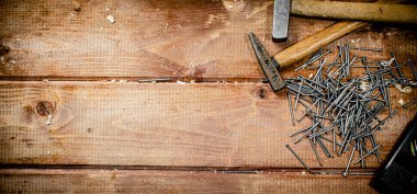 Hammer with a bunch of nails on the table. On a wooden background. High quality photo