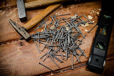Hammer with a bunch of nails on the table. On a wooden background. High quality photo
