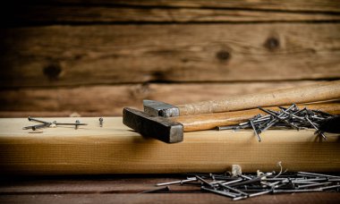 Hammer with a bunch of nails on the table. On a wooden background. High quality photo