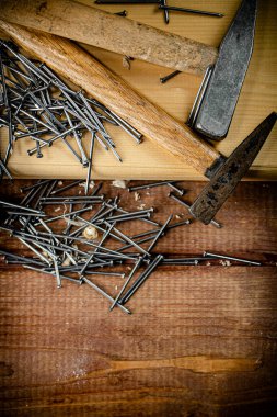 Hammer with a bunch of nails on the table. On a wooden background. High quality photo