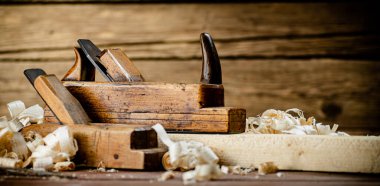 Working tool. Planer with wooden shavings. On a wooden background. High quality photo