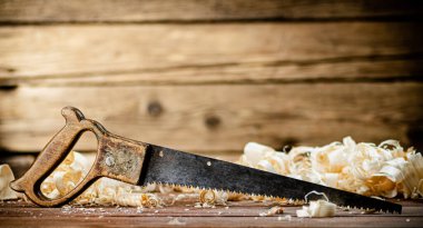 Hand saw with wooden shavings. On a wooden background. High quality photo
