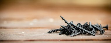 Self-tapping screws on the table. On a wooden background. High quality photo