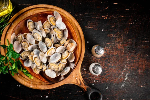 Vongole on a wooden plate with parsley. On a rustic dark background. High quality photo