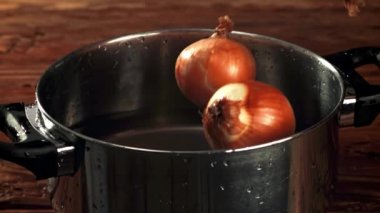 Soğan suyla birlikte tavaya düşer. Film, yavaş çekim 1000 fp. Yüksek kaliteli FullHD görüntüler