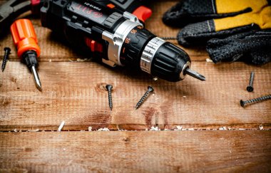Working tool. Screwdriver with self-tapping screws on the table. On a wooden background. High quality photo