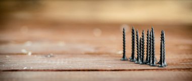 Self-tapping screw on wood on the table. On a wooden background. High quality photo
