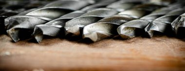 Drill bits for drills on the table. On a wooden background. High quality photo