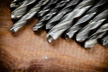 Drill bits for drills on the table. On a wooden background. High quality photo