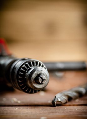 Drill with drills on the table. On a wooden background. High quality photo