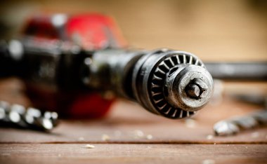 Drill with drills on the table. On a wooden background. High quality photo